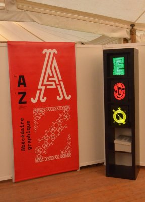 Bannière d'entrée d'exposition et les 3 boites lumineuses mettant en valeur de manière colorée les lettres E, G et Q. Présentation à la Fête du livre de Bron (69)