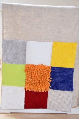 Panneau "Touche-moi !" et ses 9 carrés de textiles colorés aux différentes textures : éponge, fourrure, velours, tricot, polaire. dentelles…de quoi chatouiller les petits doigts !