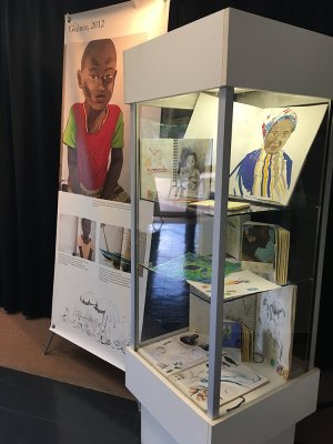 Kakémono Guinée, 2012 et carnets de voyage, recherches, crayonnés présentés dans une vitrine colonne.