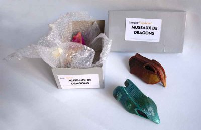 Éléments de scénographie : Museaux factices de dragons réalisés en papier mâché et peints à disposer, tels de véritables trophées de chasse, dans une vitrine.