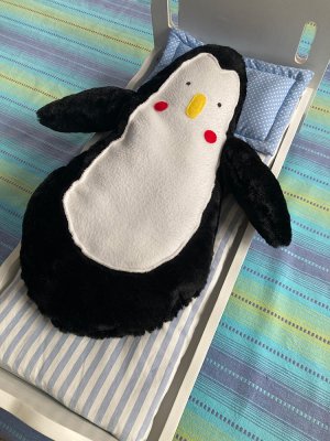 La poup&eacute;e en peluche souple "Marcel" dans son Lit.