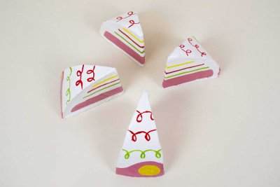 G&acirc;teau en carton et papier m&acirc;ch&eacute; peint coup&eacute; en 4 parts. Dimensions (Lxhxp) : 10x13x13 cm.