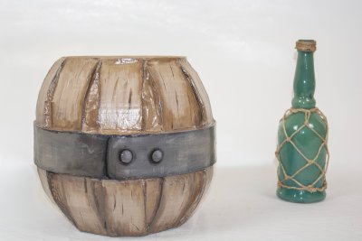 Tonneau en mousse et papier m&acirc;ch&eacute; peint avec bouteille de rhum. Mise en sc&egrave;ne d'une &eacute;tape de la chasse au tr&eacute;sor. Dimensions(26x26 cm) et(&Oslash;=9xL=30cm).