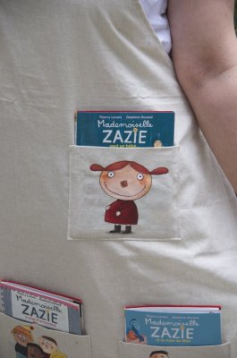 Détail d'une poche du tablier de lecture. Chacune de ces poches laisse apparaître le titre de l'album qu'elle contient, et présente une illustration spécifique à l'histoire de celui-ci.
