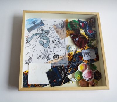 Boitage à poser à plat, présentant la reconstitution de l'espace de travail de l'illustrateur comme un "mini-atelier".