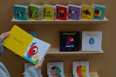 Étagères du panneau de présentation des livres d'Anne Crahay disposées sur du module d'activités en bois.