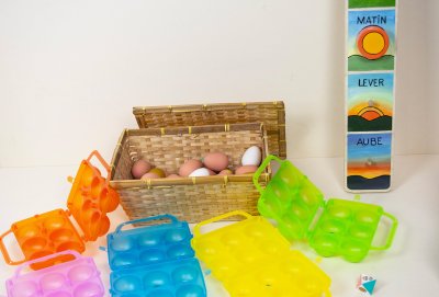 25 &oelig;ufs bruns, 5 blancs et 5 dor&eacute;s, rang&eacute;s dans un panier en osier &agrave; couvercle et 5 bo&icirc;tes &agrave; &oelig;ufs vides color&eacute;es.