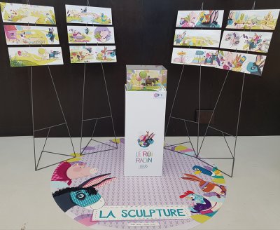 Ensemble des 12 illustrations double page de l'album, pr&eacute;sent&eacute;es 3 par 3 sur leur syst&egrave;me d'installation en m&eacute;tal, avec en son centre la pr&eacute;sentation sur plot de la sculpture.